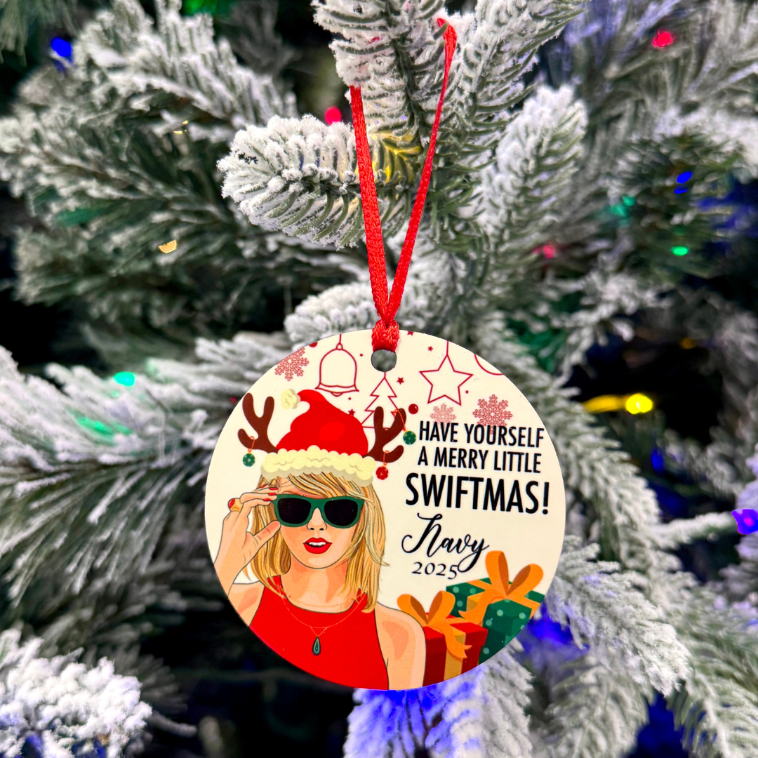 Custom Swiftmas ornament with red ribbon and holiday lights in the background — festive Christmas tree decoration.